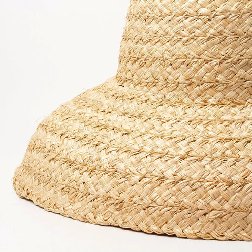 Chapeau de Plage Femme en Raphia sur un mannequin, large bord, parfait pour les journées ensoleillées.