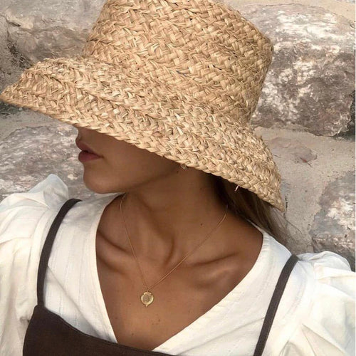 Chapeau de Plage Femme en Raphia sur un mannequin, large bord, parfait pour les journées ensoleillées.