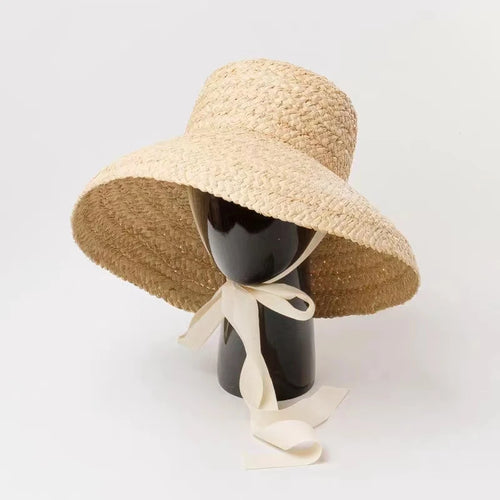 Chapeau de Plage Femme en Raphia sur un mannequin, large bord, parfait pour les journées ensoleillées.