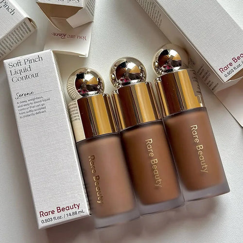 Stick Contouring nacré & Illuminateur – Contrôle Sébum by Rare Beauty in various shades displayed on a vanity.