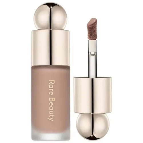 Stick Contouring nacré & Illuminateur – Contrôle Sébum by Rare Beauty in various shades displayed on a vanity.