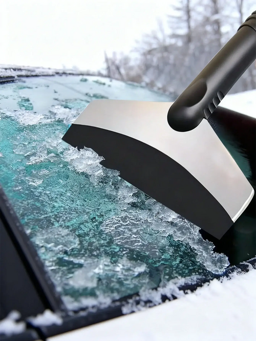 A person using a Grattoir à Glace & Brosse à Neige Universel to clear snow from a car windshield.