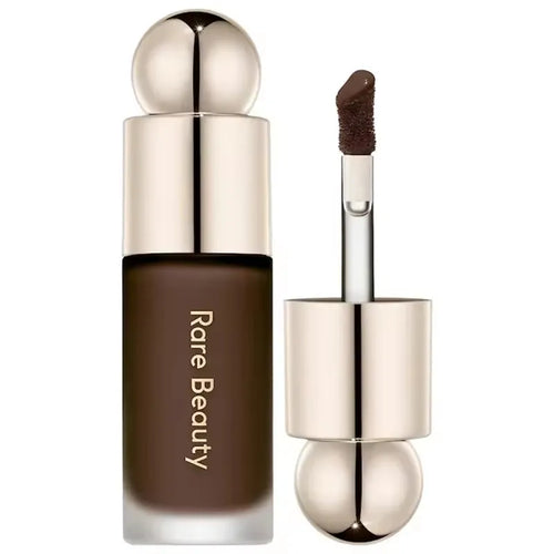 Stick Contouring nacré & Illuminateur – Contrôle Sébum by Rare Beauty in various shades displayed on a vanity.