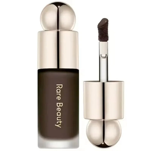 Stick Contouring nacré & Illuminateur – Contrôle Sébum by Rare Beauty in various shades displayed on a vanity.