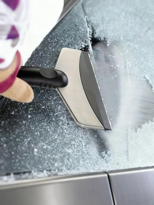 A person using a Grattoir à Glace & Brosse à Neige Universel to clear snow from a car windshield.