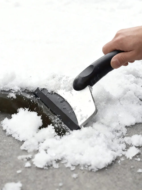 A person using a Grattoir à Glace & Brosse à Neige Universel to clear snow from a car windshield.
